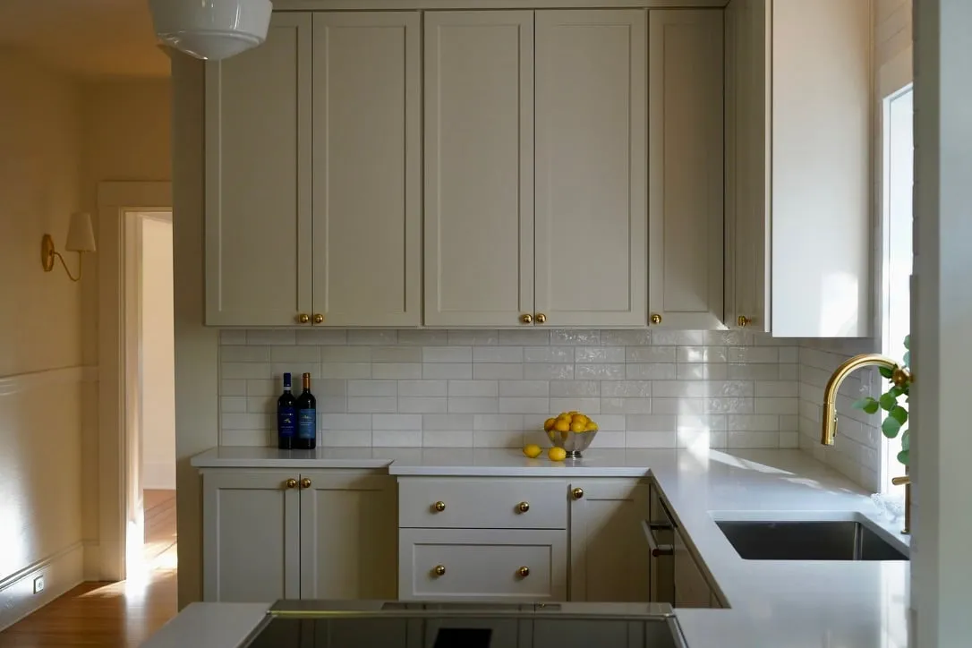 Remodeled white kitchen with brass fixtures in NE Portland by Noema Interior Design